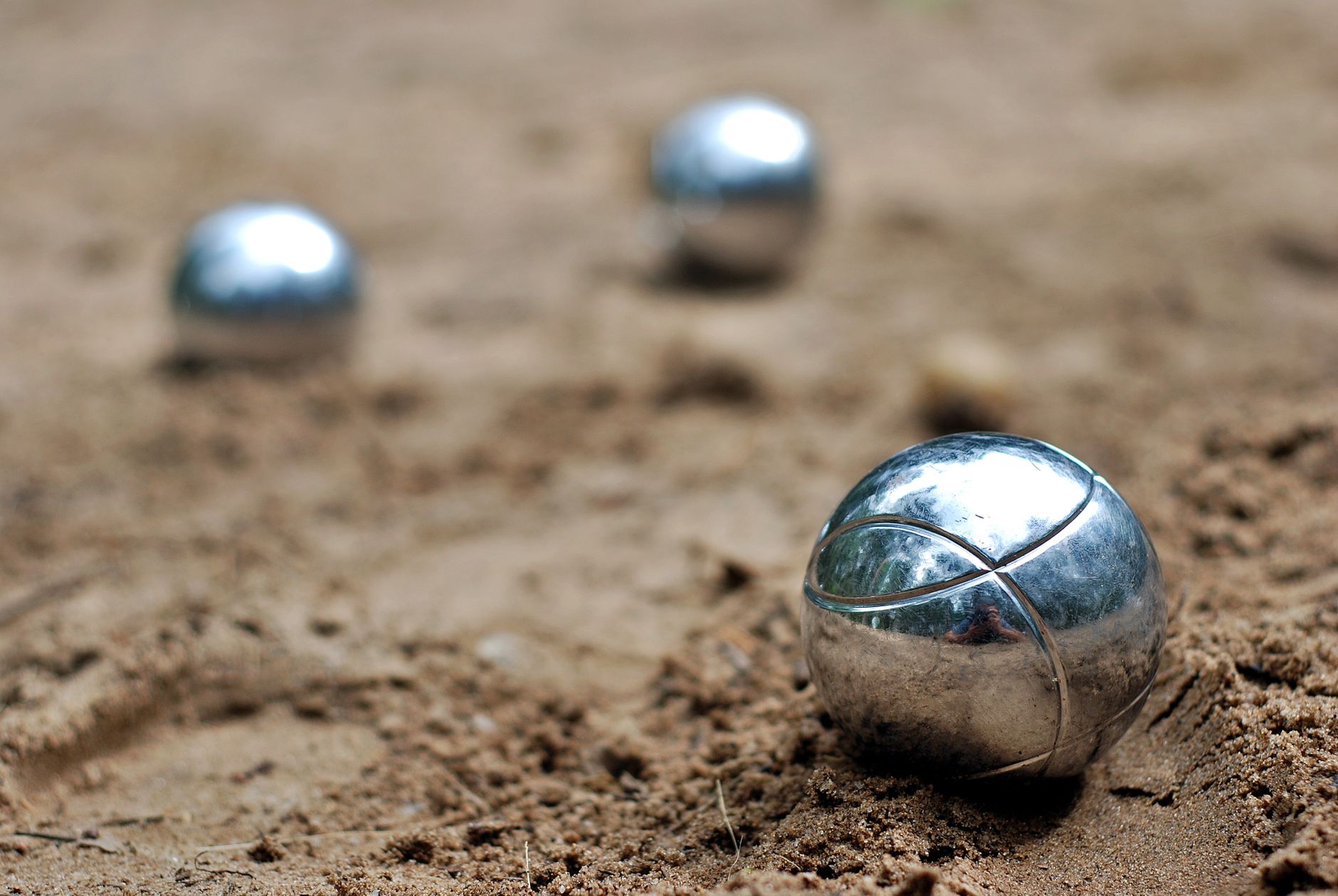 A weathered iron cannonball resting in wet beach sand near a metal detector